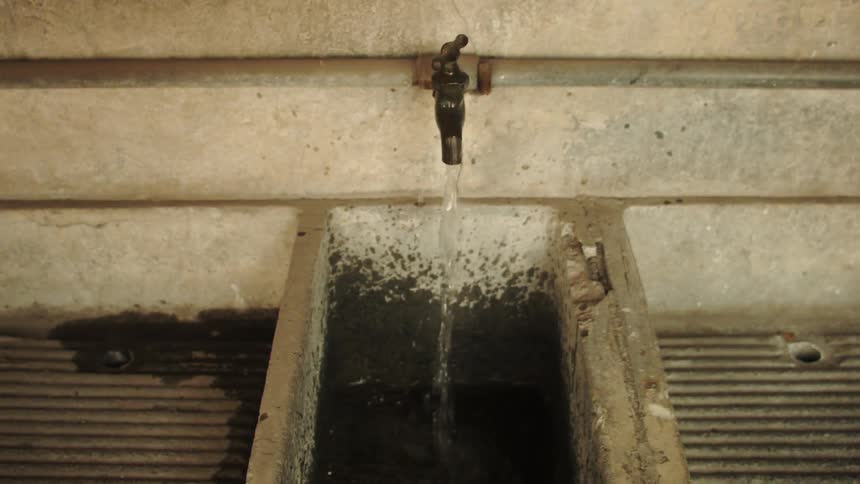Running faucet with flowing water in a concrete tank