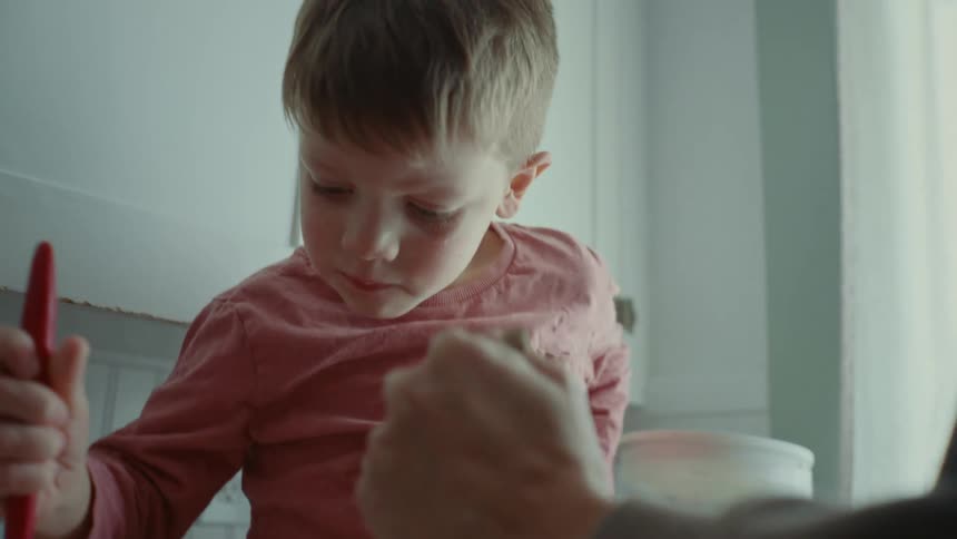 A mother and son mix food in the bowl