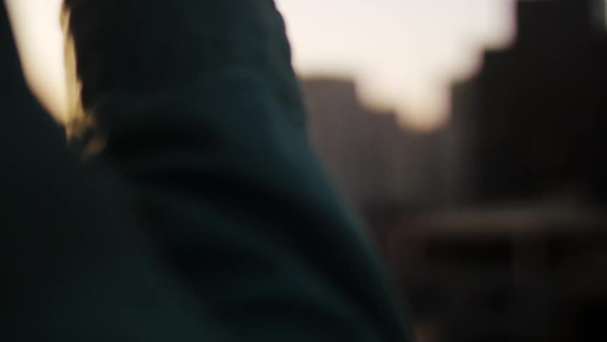 Man wearing a blue shirt drinks from a white cup watching the city landscape
