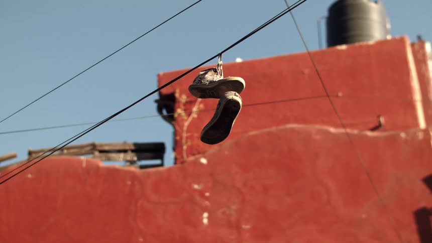 A pair of shoes hanging by a thread during the day