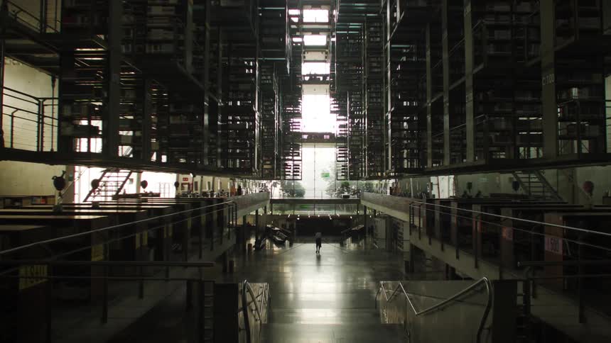 A person walking in the building hallway towards the exit