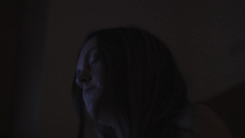 A woman is rocking back and forth in the dark