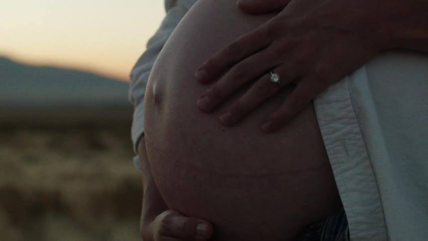 A pregnant woman stroking her big belly