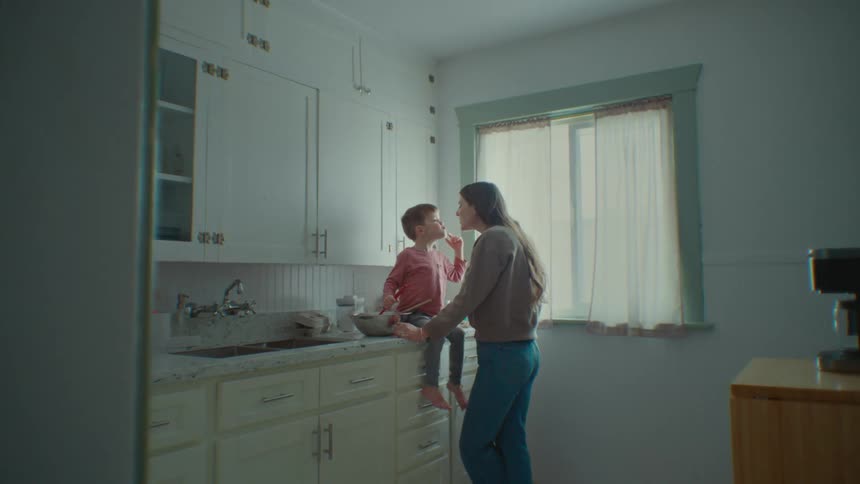 A mother kisses her son as they cook at home