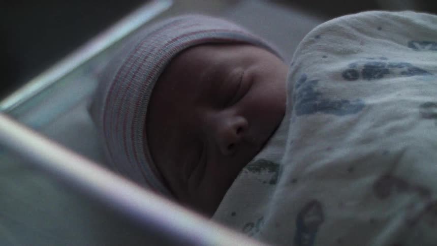 A baby sleeps in an incubator type device