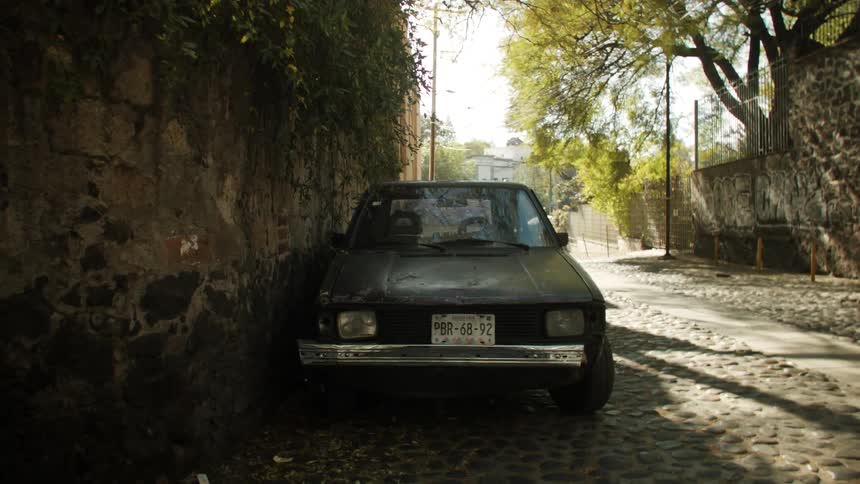 A car parked on a cobblestone street next to a wall