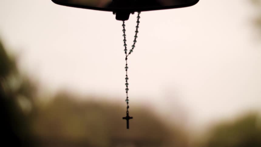 A crucifix hanging from a rear view mirror