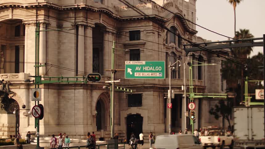 A busy street with a crosswalk in front of a classically designed building
