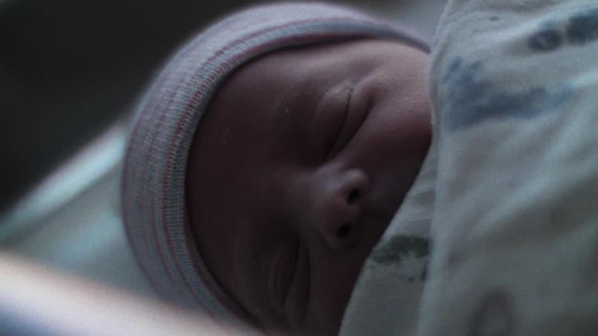Portrait of a newborn baby in a crib