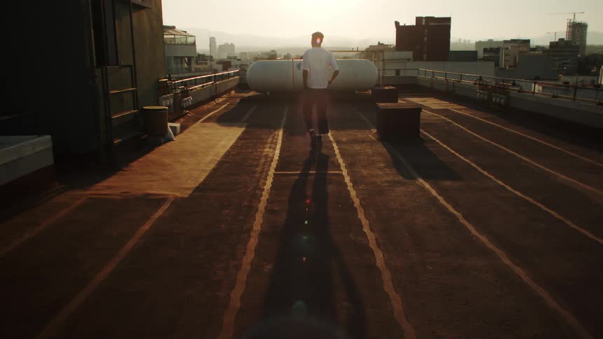 A person on a rooftop admires the sunset and the city view