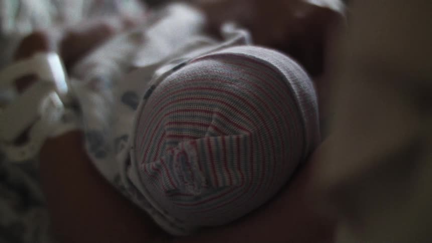 Closeup of a persons arm holding a newborn