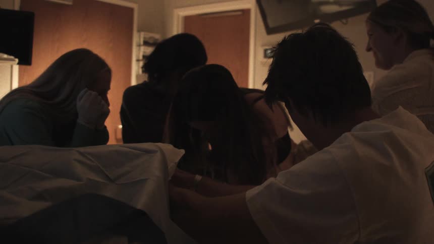 People huddled together in a darkened hospital room