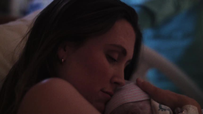 Mother cradles baby while lying in hospital bed