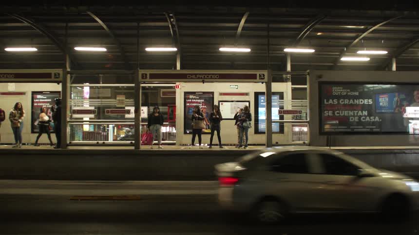 People wait for a bus at a station in a city