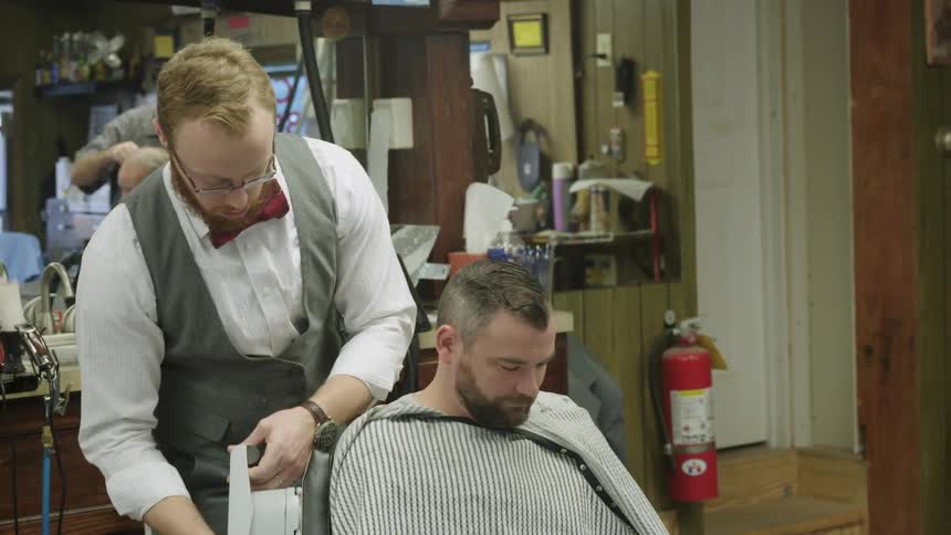 Barber using a massager on a mans shoulder