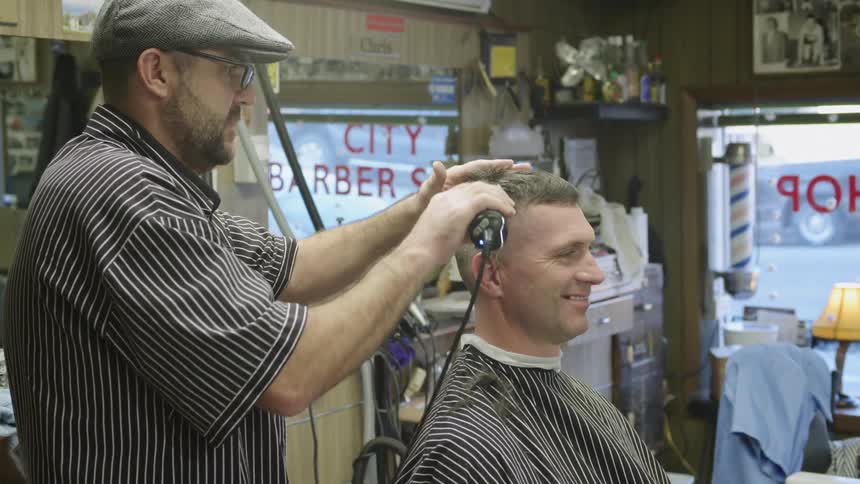 A man is getting his hair shaved by a barber