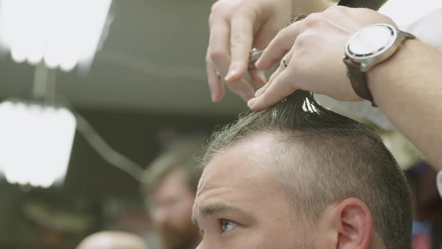 A barber is cutting a man's hair with scissors