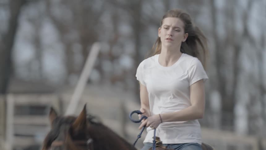 A young woman rides a horse through a field