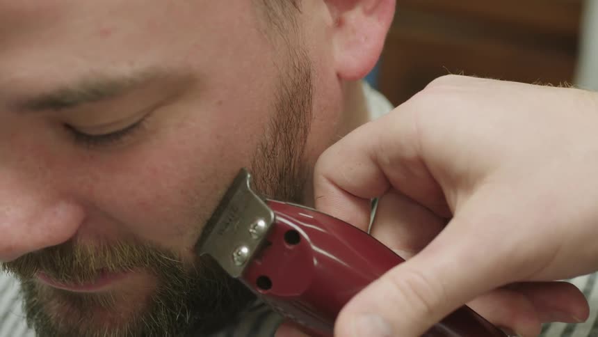 A barber trims a man's beard