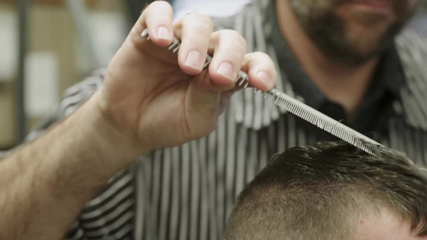 A barber is using a comb to style a customer's hair