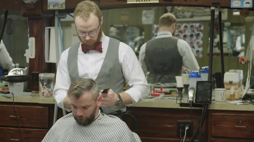 Man cutting another man's hair at a barber shop