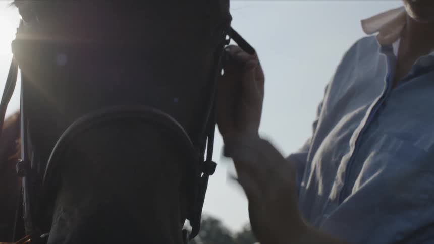 Woman checks gear on a horse