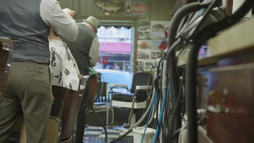 Two barbers cutting hair in barber shop