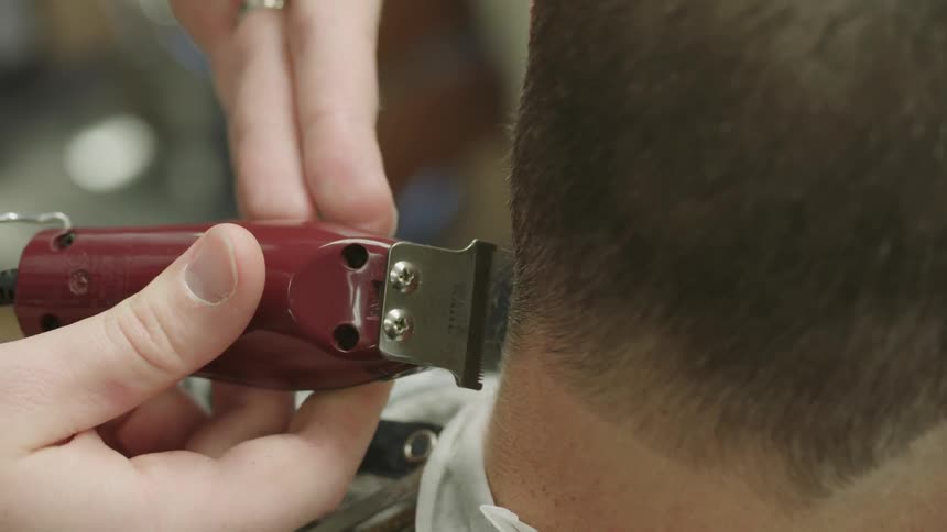 Barber uses an electric razor on a customer