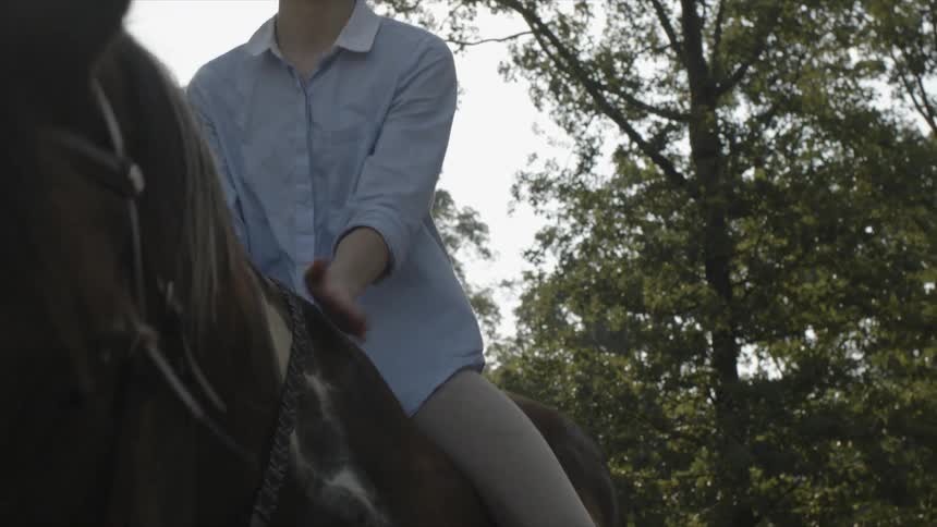 A woman riding a horse pats and rubs its shoulder