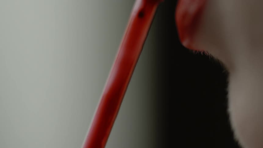 A woman applies bright red lipstick