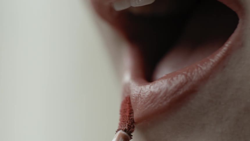 A woman applies tinted lip gloss