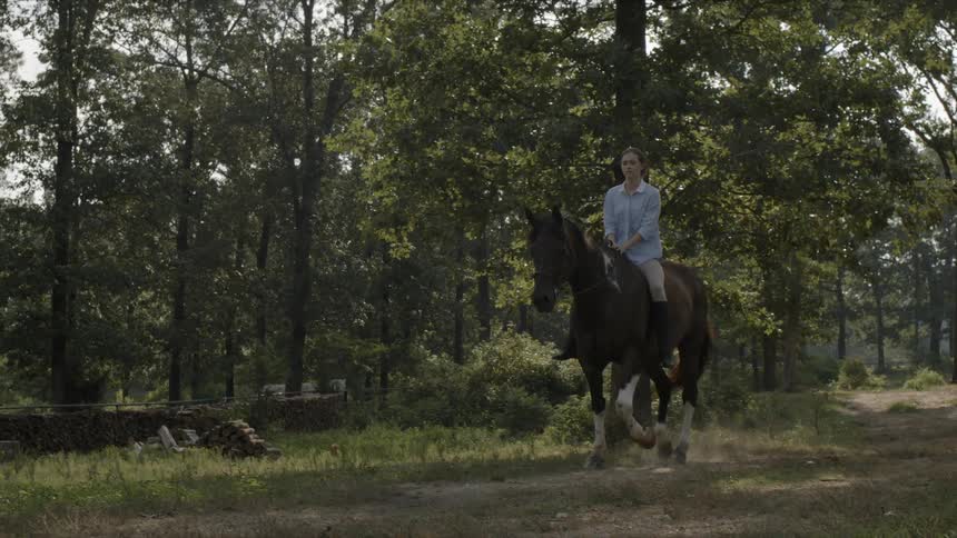 A woman is riding a horse bareback on a trail