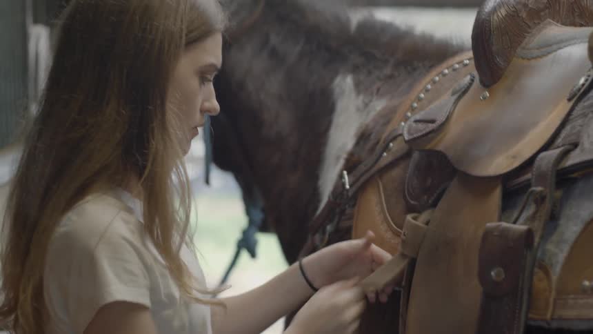 Woman securing a saddle on a horse