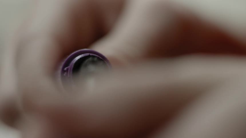 A woman removes a brush cap from a bottle of makeup