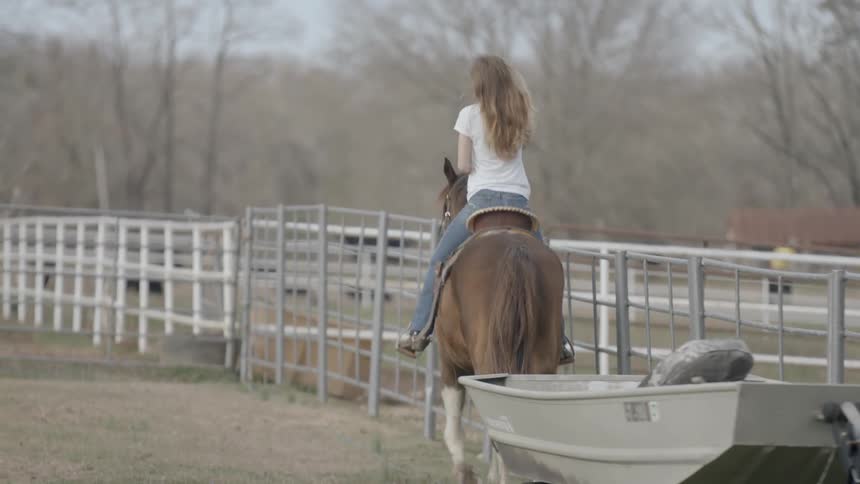 A woman in white rides a horse in a circle