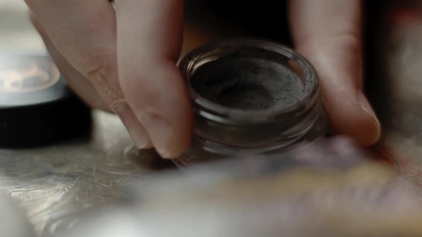 A person places a makeup jar on a tray