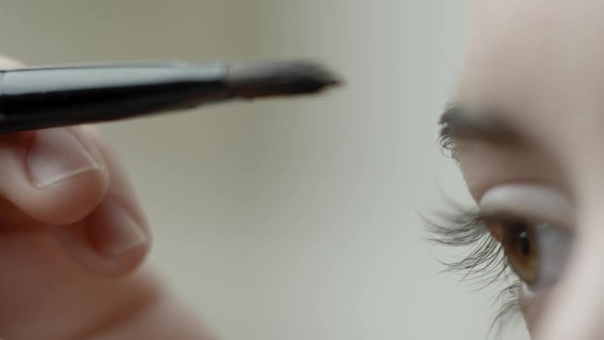 A woman applies makeup using a brush