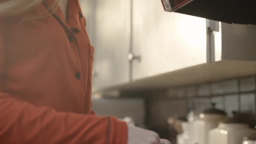 Woman in kitchen stirring a hot drink in tea cup