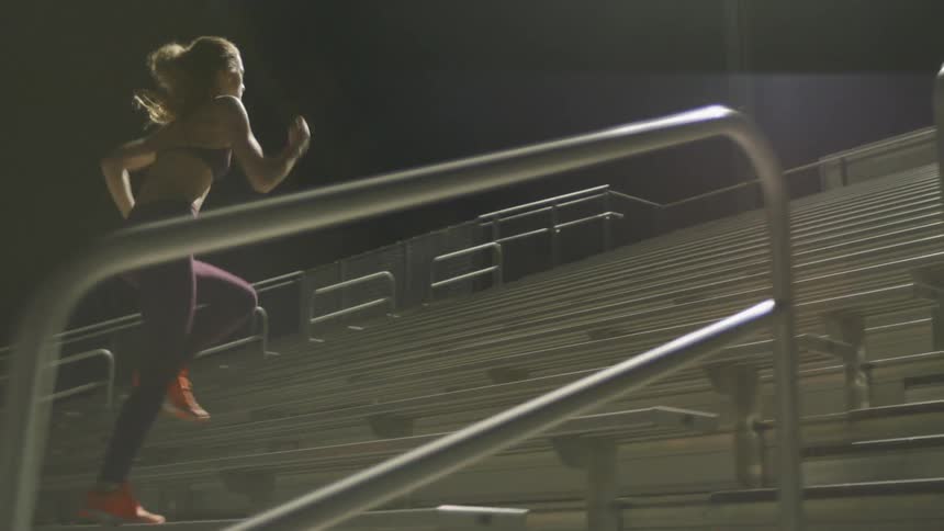 A female athlete powers up a stand of bleachers in a stadium