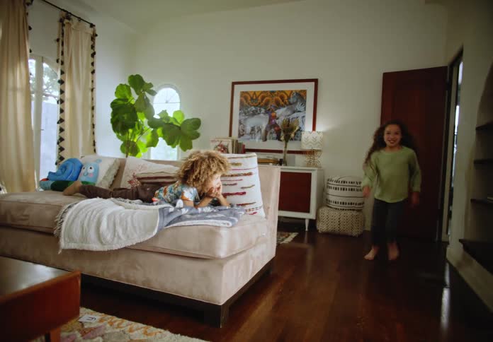 A child runs into a living room and yells loudly