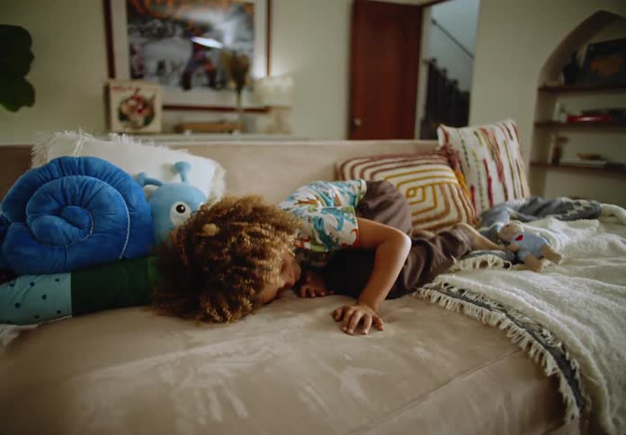 Boy in the living room jumping and throwing himself on the sofa