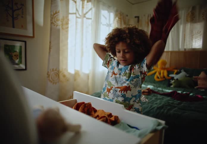 Boy taking his clothes out of the closet and throwing himself on the bed
