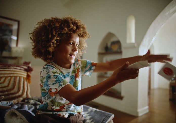 Child with curly hair plays with cards indoors