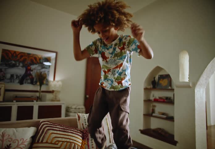 Little boy climbing on the sofa and jumping happily