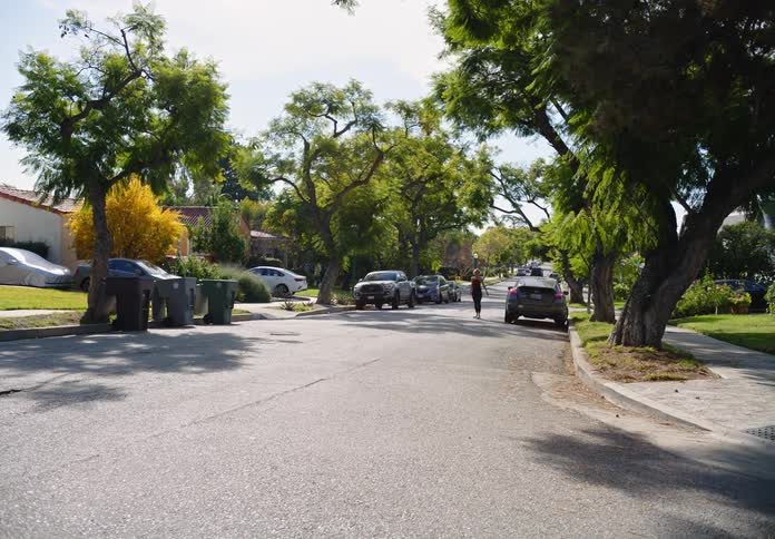Woman runs and skips down residential street on a sunny day