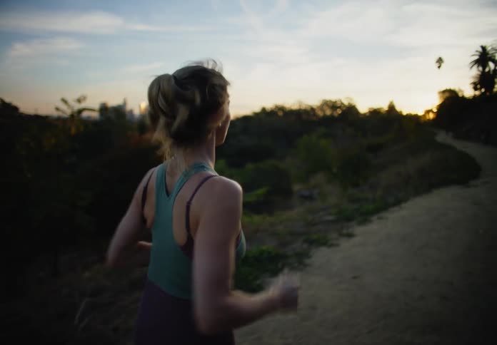 Woman in fitness clothes running in an open woodland one morning
