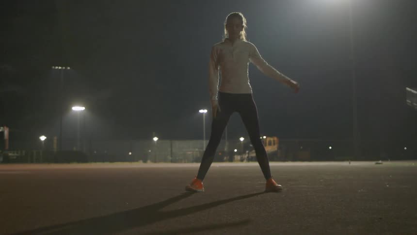 A woman stretches near stadium bleachers