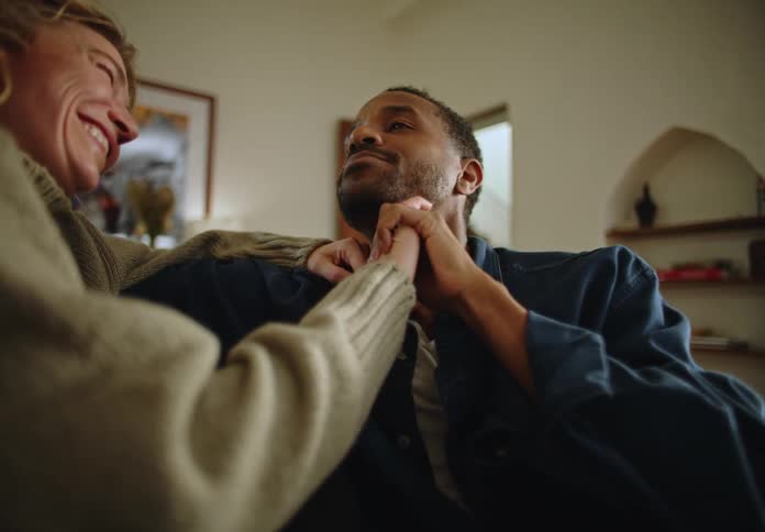 Man and woman seated inside the bedroom talking while holding hands during the day