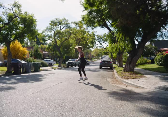 A woman jumps and runs down the street