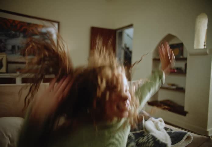Two children in the living room playing and jumping on the sofa